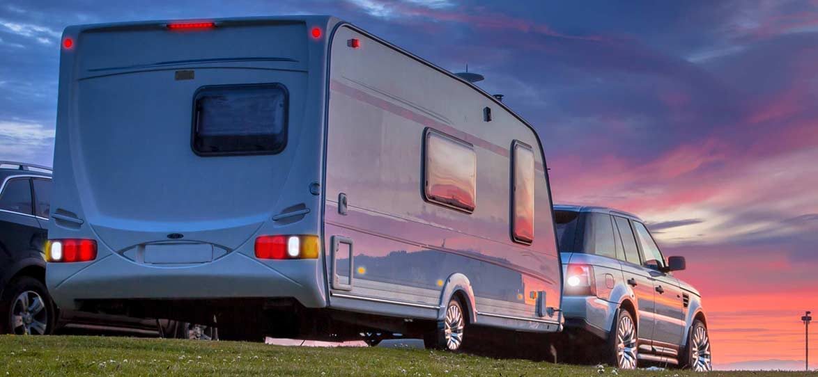 Gespann aus Zugfahrzeug und Wohnwagen in der Abenddämmerung